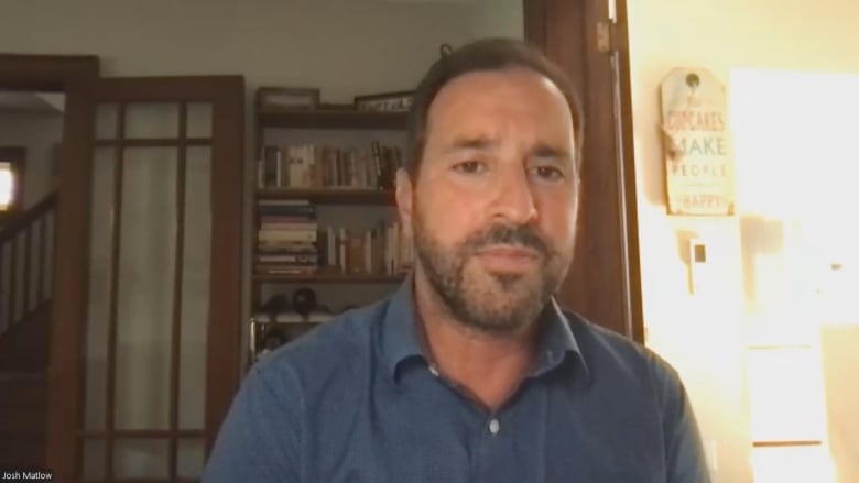 Photo of a man during a Zoom call in a button-up blue shirt.