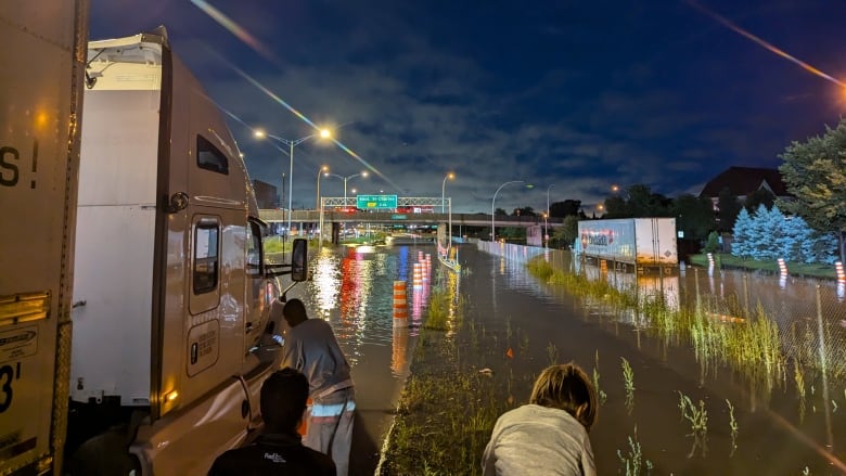 A large truck and several cars on a flooded highway.