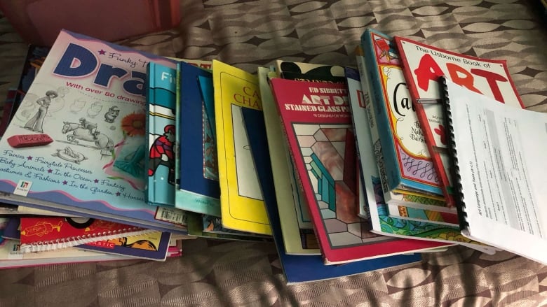 A collection of books lays on top of a bed. 