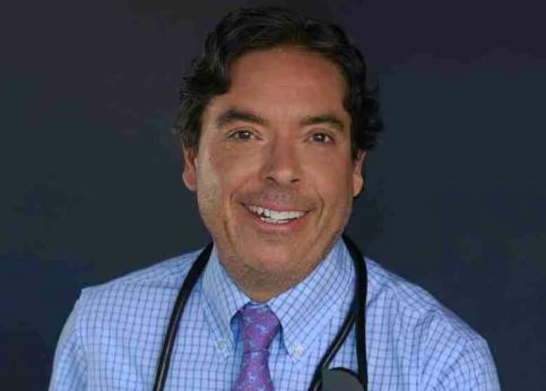 A smiling man wearing a stethoscope