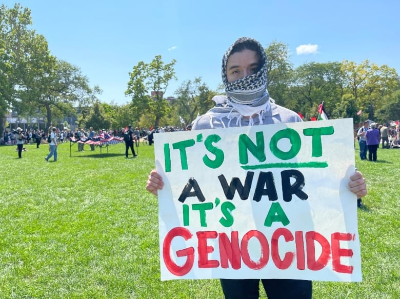 An anti-Israel protester stands with a placard.