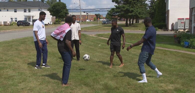 A number of the players from TSI (The Soccer Initiative) kick a ball around the grounds of an apartment building in Charlottetown.