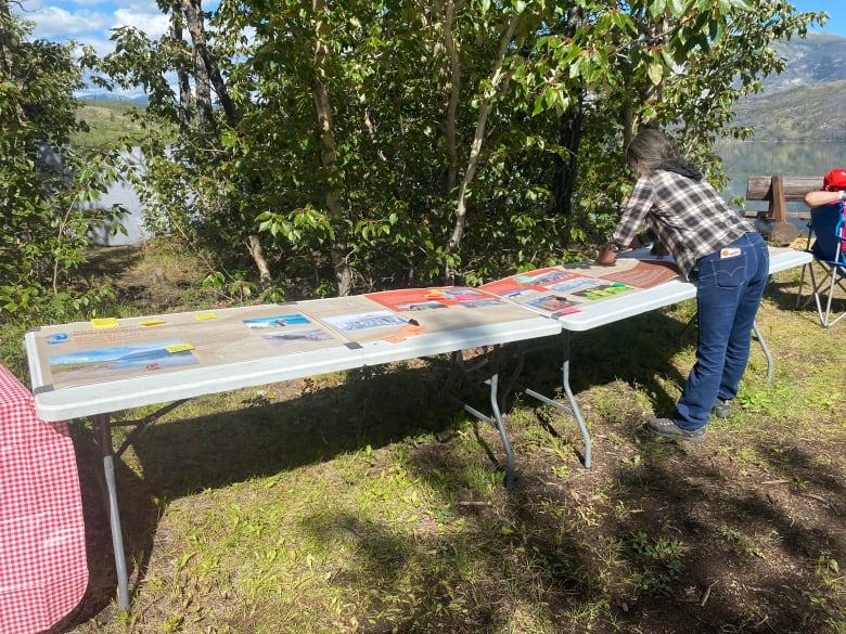 A woman leans across a table where signs are printed out 