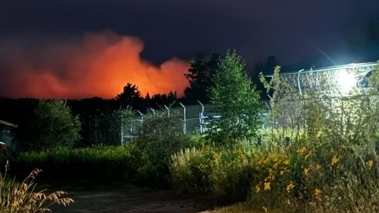 An outdoor photo with a bright red light and smoke coming from the distance