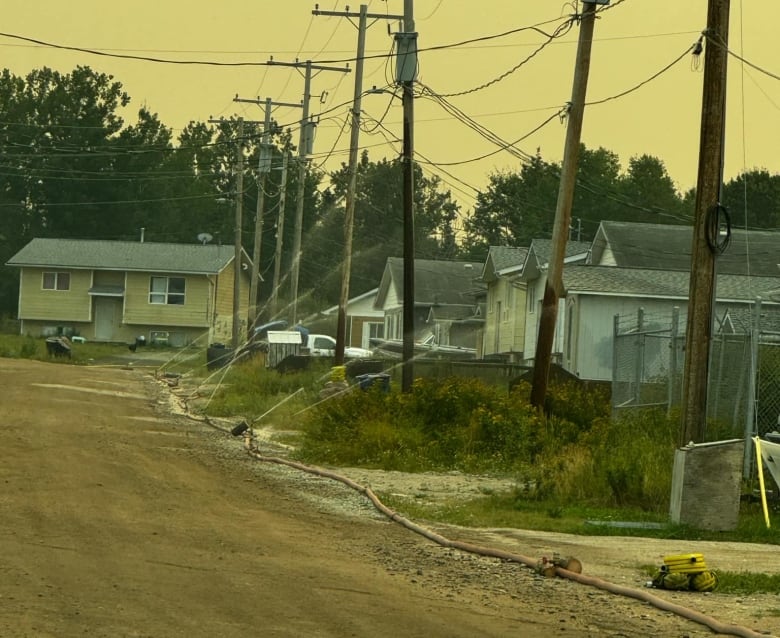 hoses laid on dirt roads spraying water in residential areas