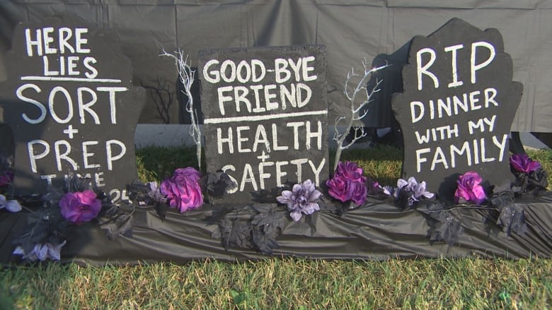 Three hand-crafted tombstones are surrounded by a black table cloth on the grass. 