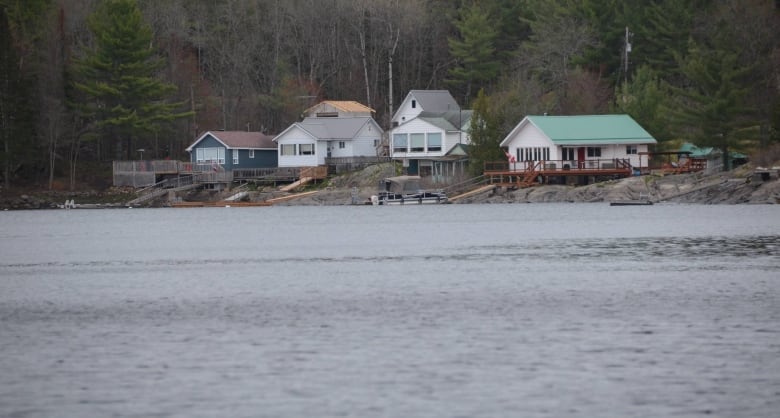 Several houses are perched on the side of the rocky shore of a lake 