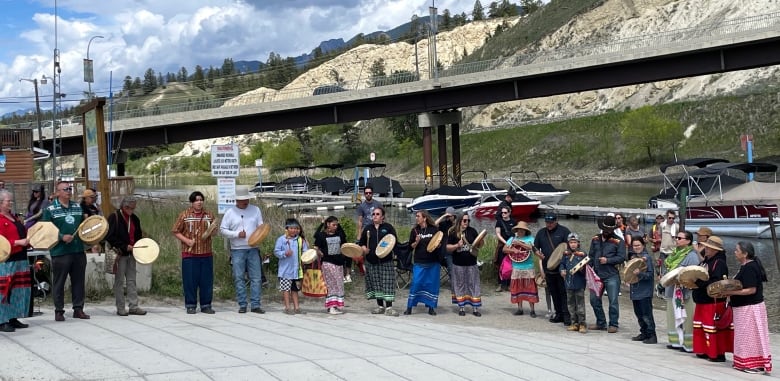 A large group, some with drums, form a semi-circle.