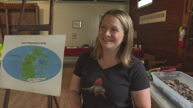 A woman stands in front of a map.