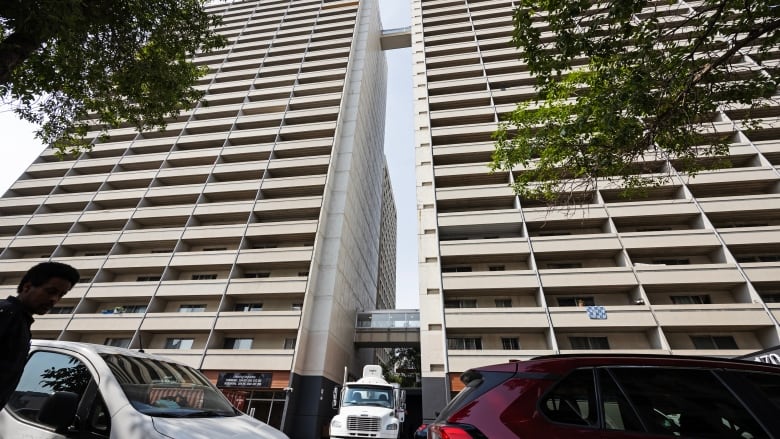 Two whit highrise building stand, a water truck is between both of them. 