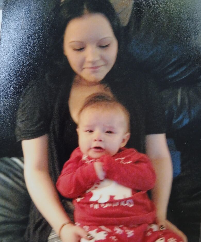 A woman and baby sit on a couch. 