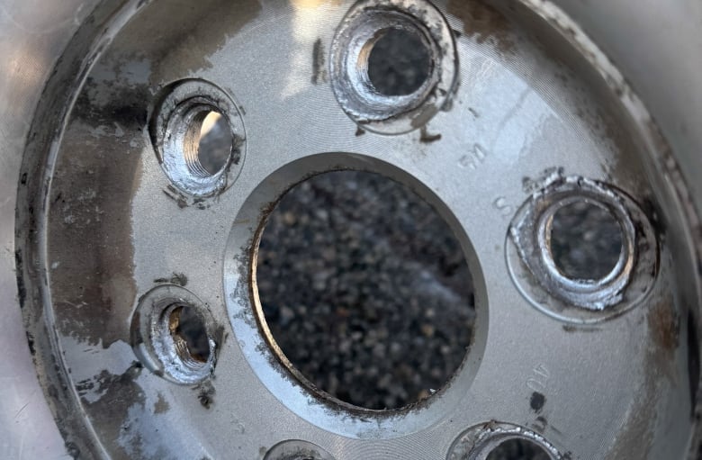 A closeup of a tire rim with the lug nuts removed.