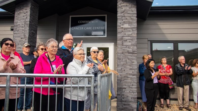 A group of people applaud in front of the Community Cancer Care Centre.