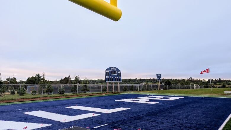 A football field with scoreboard in background. 