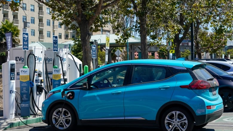 A blue electric car charges at a charging station