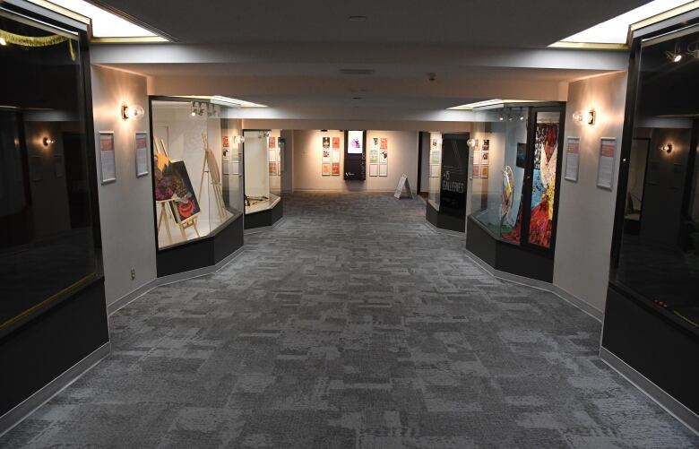 Along an indoor hallway, art is displayed in a number of window front galleries.