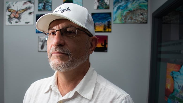 A man in a baseball cap looks serious.