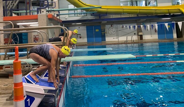 Three swimmers getting ready to dive off of platforms. 