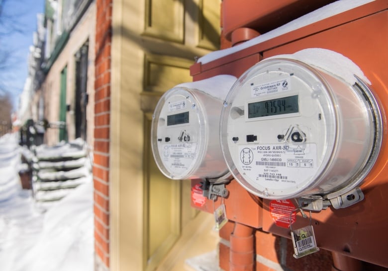 Electrical meters on the side of the house with snow-covered stairs in the background