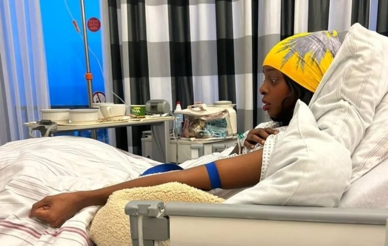 A Black woman rests in a hospital bed.