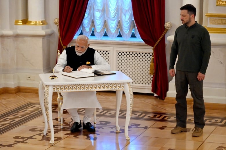 Ukrainian President Volodymyr Zelenskyy looks on as Indian Prime Minister Narendra Modi signs a guest book at Kyiv's Mariinskyi Palace.