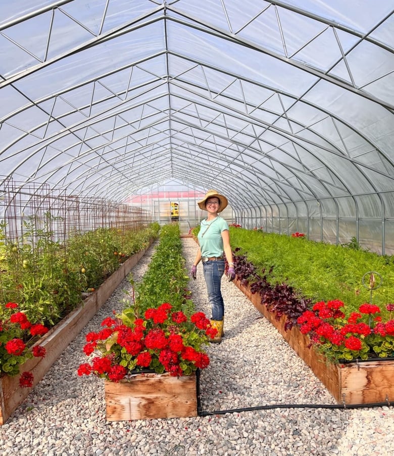 Woman in hat and rainboots stands in garden