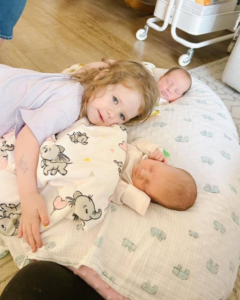 A young child hold two babies.