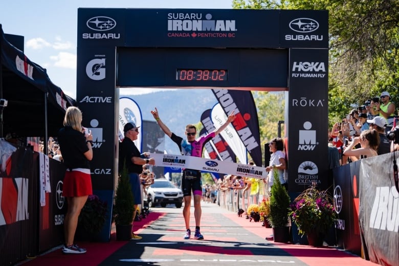 An athlete celebrates has he reaches the finish line with onlookers cheering.