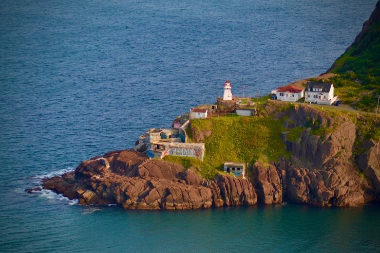 A small lighthouse and old fort on the edge of a cliff.