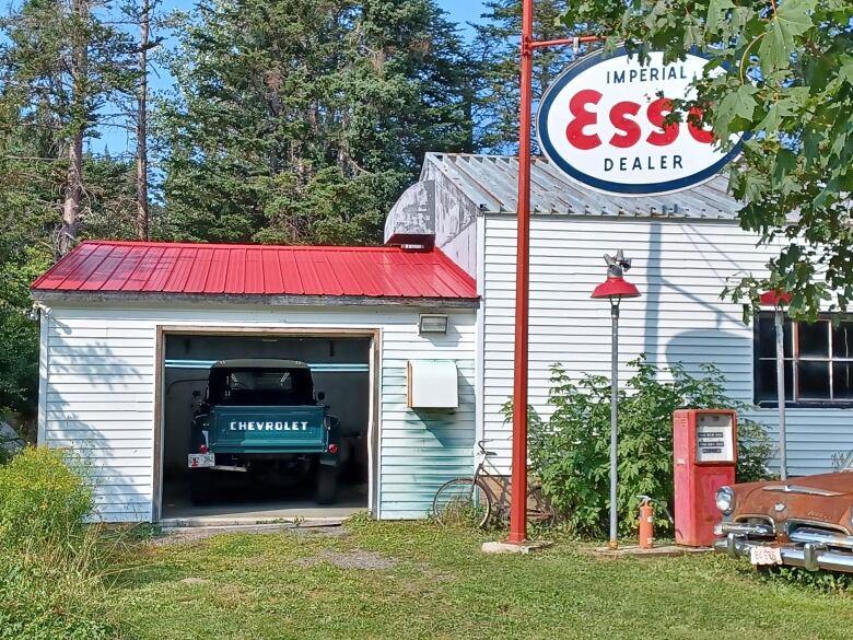 An old fashioned gas station with a pair of antique autos still there.