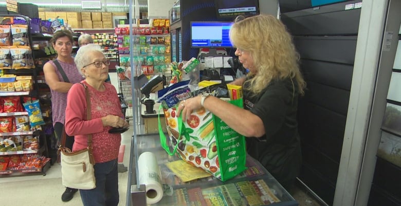 A cashier puts groceries into a reusable bag.