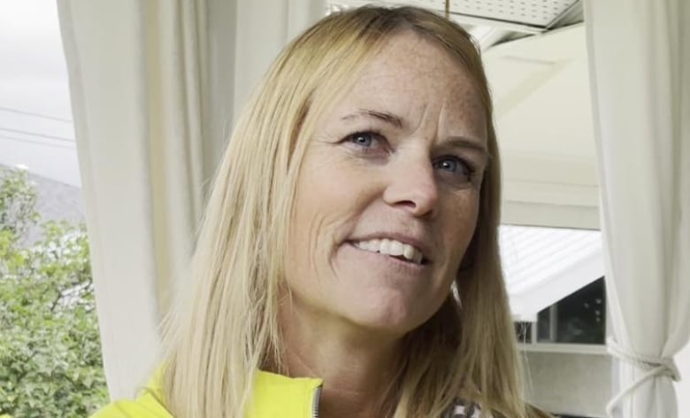 A portrait of a blonde woman in yellow jacket.