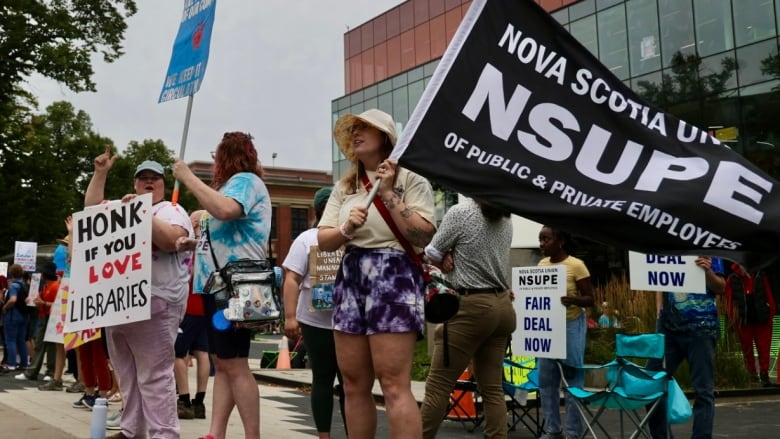 people holding signs in front of building.