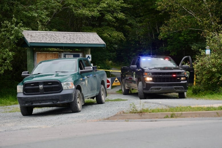 Two vehicles park in front of a trail 