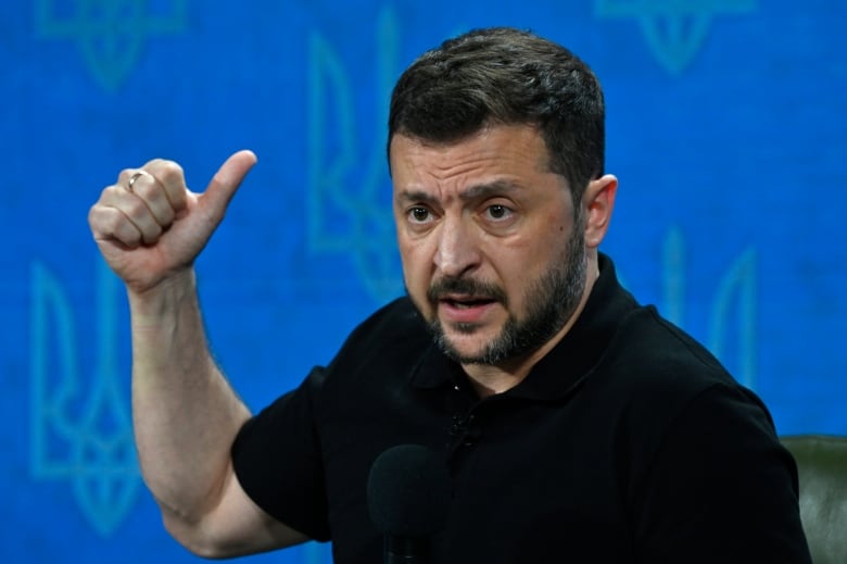 Ukrainian President Volodymyr Zelenskyy is seen making a gesture while speaking at a press conference in Kyiv.