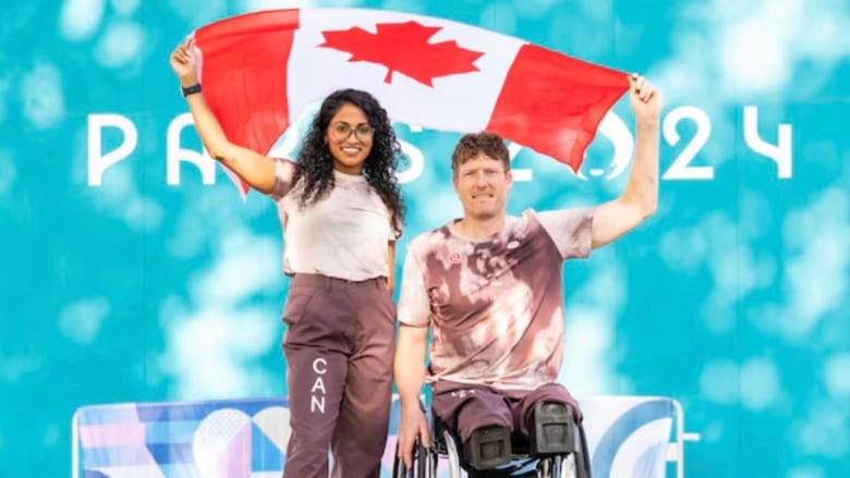 Two athletes hold the Canadian flag together.