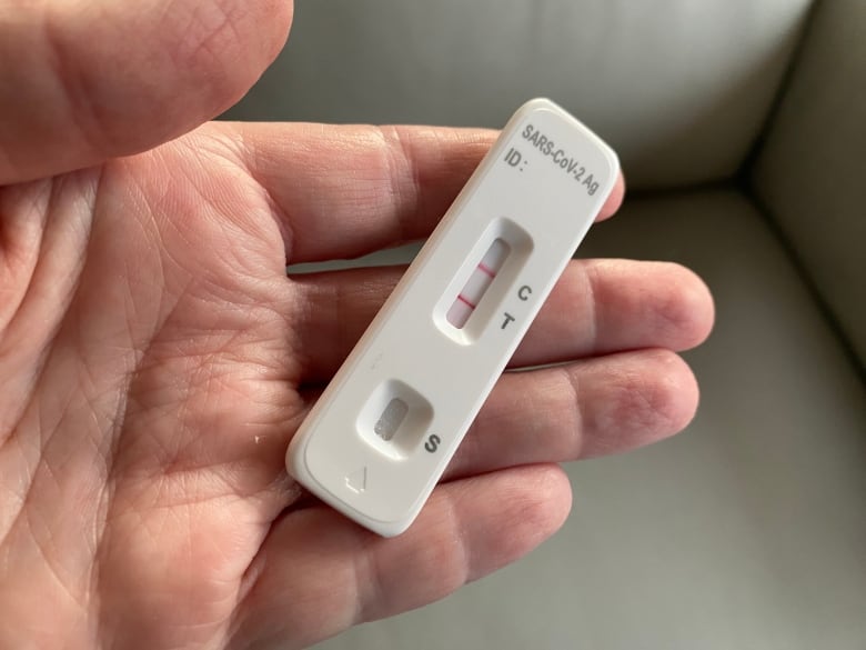 Closeup of a hand holding a positive COVID 19 test in March 2024.