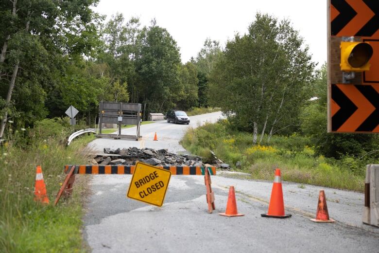 A sign that reads bridge closed is placed in front a large gap in the road where there was once a bridge. 