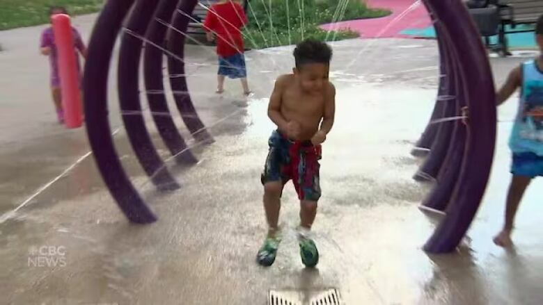 A little boy runs through spraying water