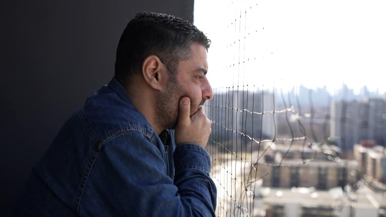 A man looks out from his balcony