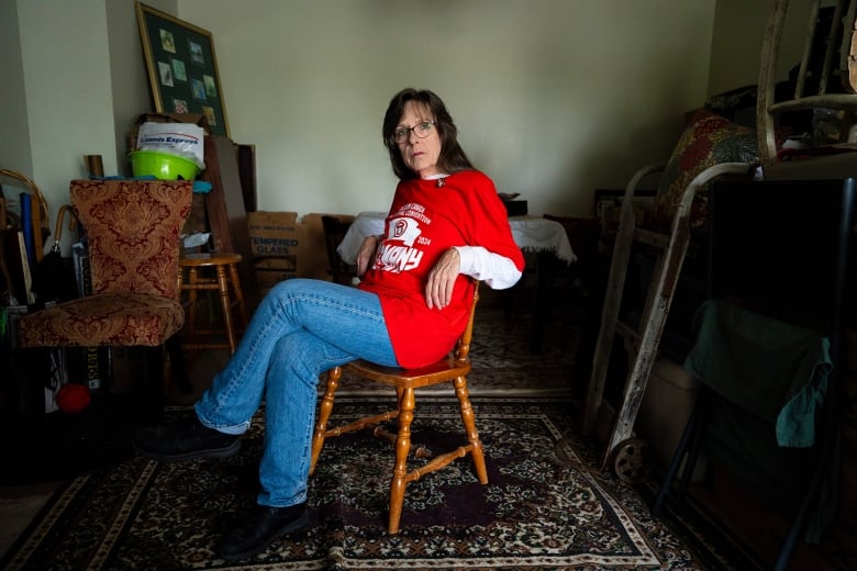 A woman sits in her darkened apartment.