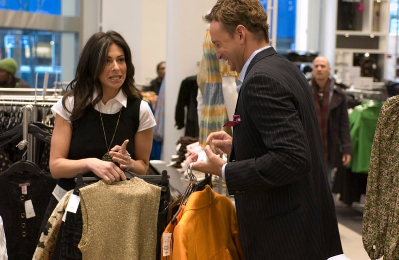 A man and a woman hold clothing in a store