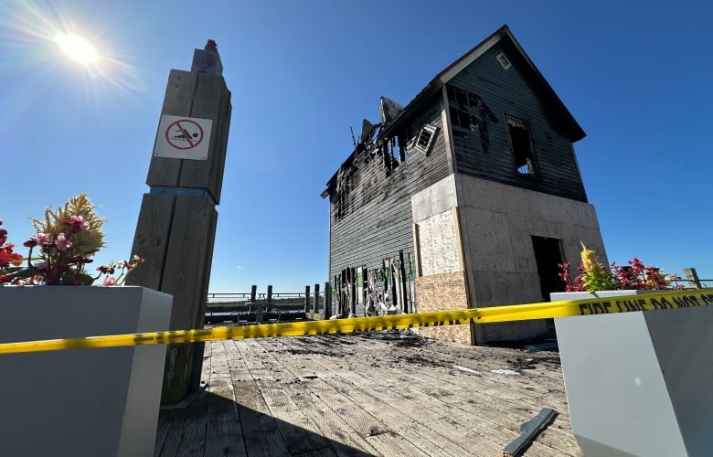 Two-storey, red-roofed building heavily damaged by fire. 