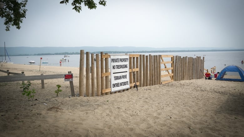 A wide image of the fence backing the 122 Lane Street property, which runs to the shoreline and into the water of the Ottawa River.