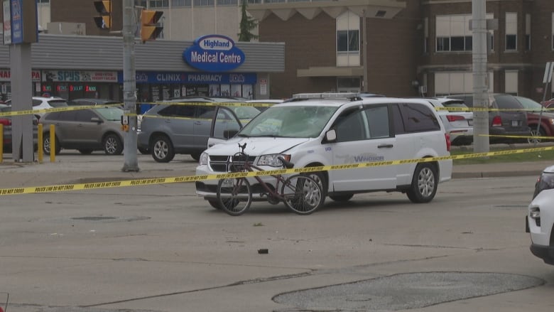 A City of Windsor van with a dented hood sits at the scene of a collision at the intersection of Howard Avenue and Tecumseh Road East on Thursday at around 12:30 p.m.  There is a bike leaning on the front of the vehicle and police tape surrounding the scene.