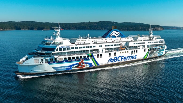 A blue and white ferry with the words B.C. Ferries on the side.