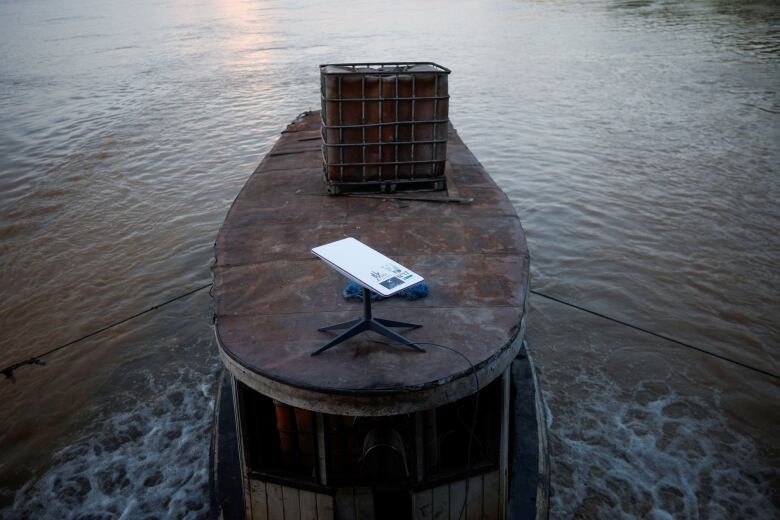 A small device on a small tripod sits on top of a metal boat in the water. 