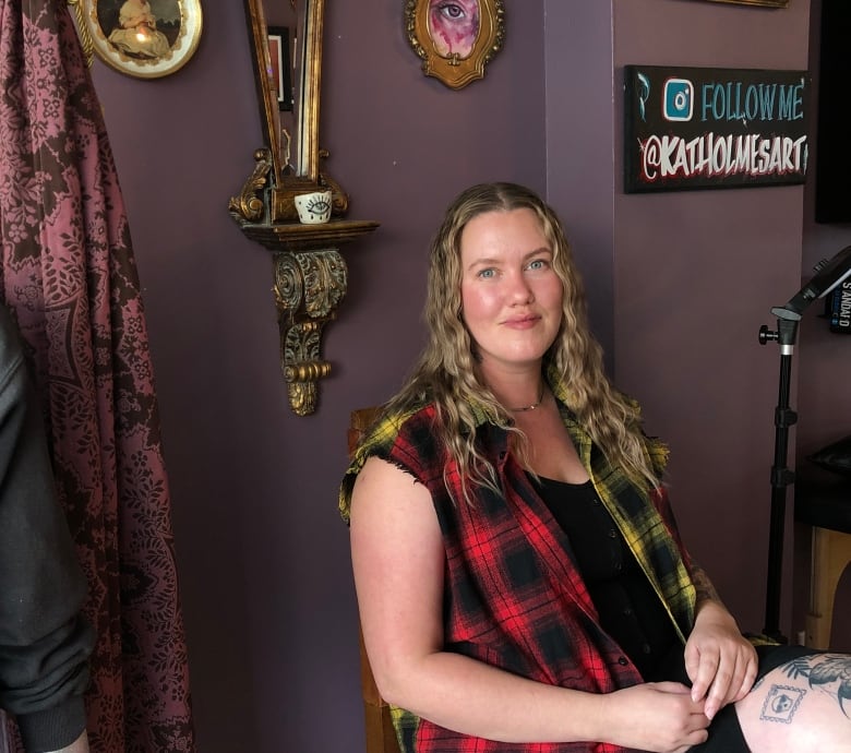 A woman sits against the wall smiling at the camera