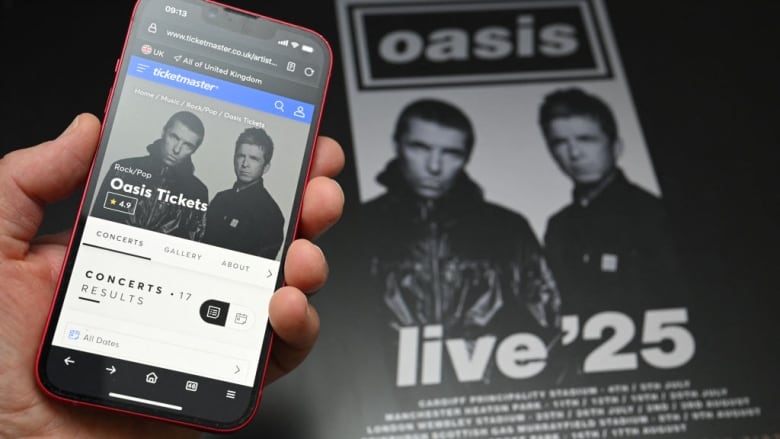 A fan holds a smartphone to access an online ticket sales website to purchase tickets for Oasis.