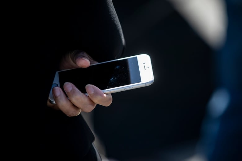 A close-up photo of a person holding a cellphone in their hands.